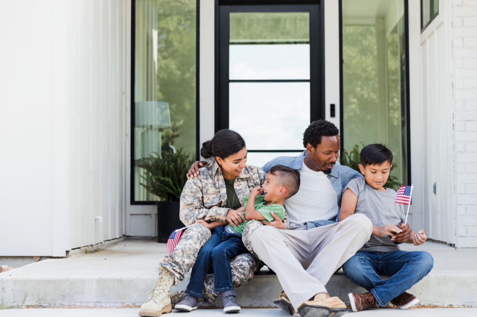 A service member in uniform and her family relaxing on the front porch of their Arizona home